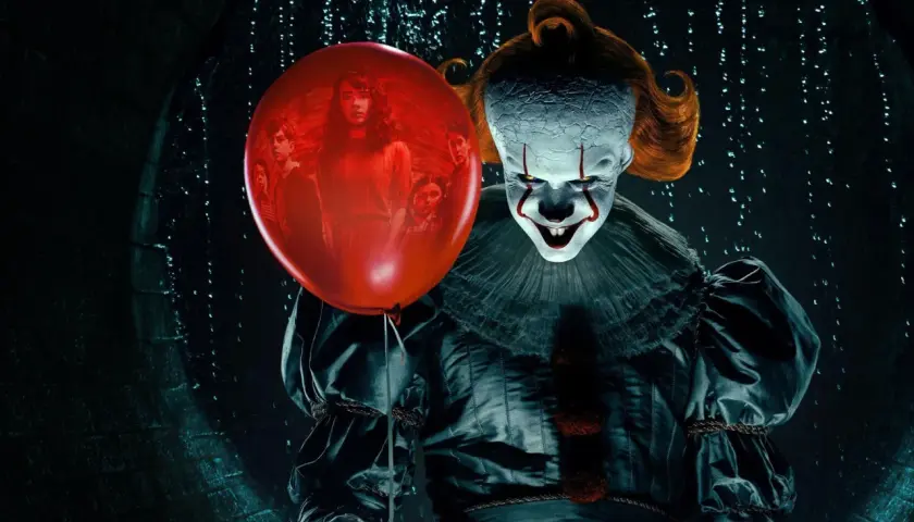 Przerażający klaun Pennywise trzyma czerwony balon, w którym widać grupę dzieci. To jeden z najlepiej ocenianych horrorów.