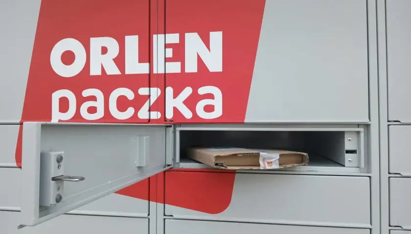 Szafka paczkomatu z logo Orlen Paczka i paczką w środku.