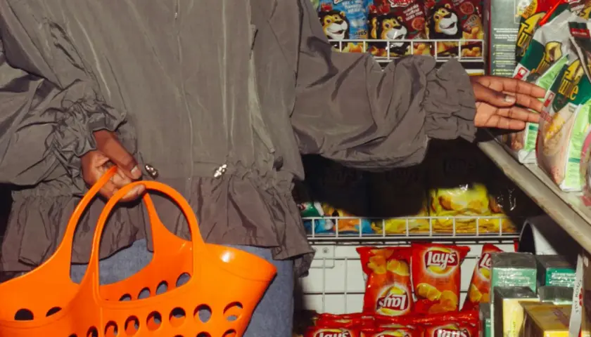 Person mit Einkaufskorb vor Chipsregal. Die **skimpflation definition** zeigt, wie Hersteller bei gleichbleibenden Preisen die Menge reduzieren.