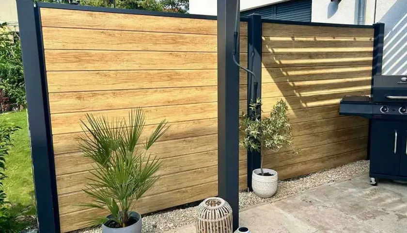 Moderner Sichtschutz aus Holz, ideal zum selber bauen. Ein Grillplatz mit stilvoller Holzwand und Pflanzen.