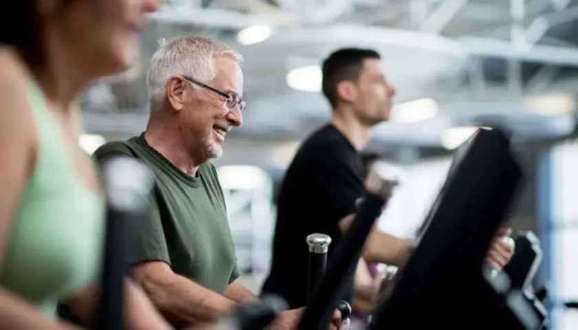 Lächelnder Mann auf Laufband im Fitnessstudio. Er genießt das Training, auch wenn er später sein Widerrufsrecht im Fitnessstudio prüfen muss.