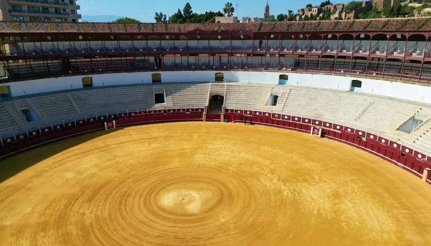 La plaza de toros de Málaga, con su arena dorada y gradas vacías, espera la próxima corrida.