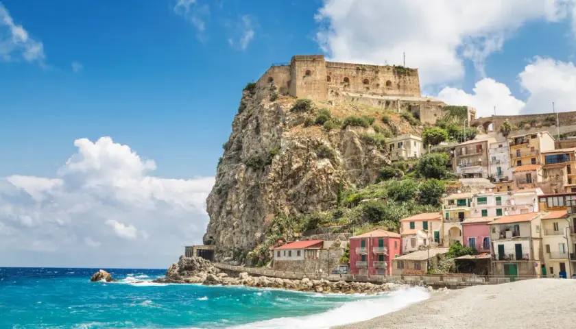 A picturesque coastal village with colorful houses clinging to a cliff, topped by an ancient castle. This is a must-see destination for anyone wondering where to go in Calabria.