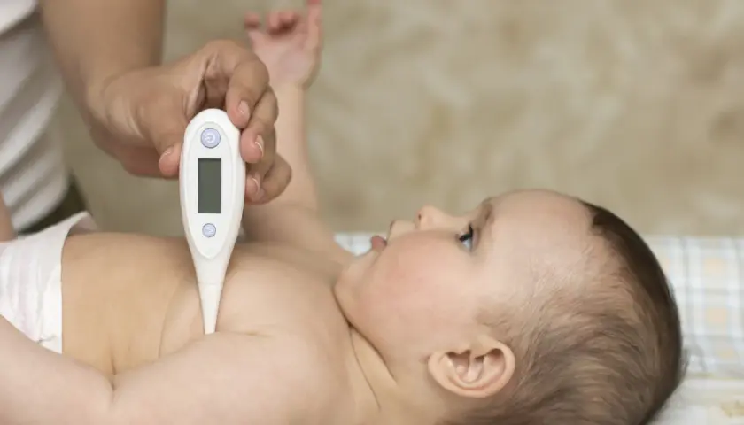 Mano mide la temperatura a un bebé con un termómetro digital. ¿Qué termómetro es más fiable?