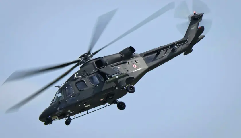 Ciemnozielone helikoptery wojskowe z polskimi szachownicami w locie.