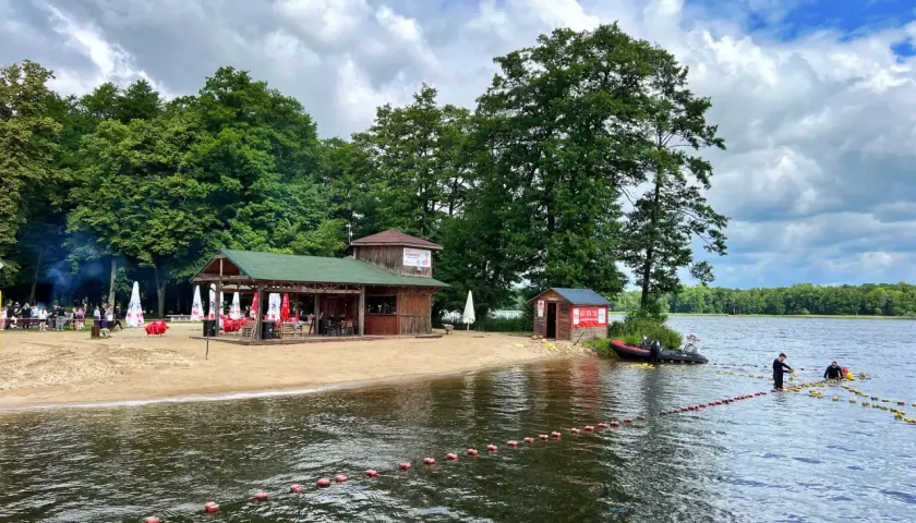 Plaża i jezioro w Szczecinku, z budynkami gastronomicznymi i ludźmi na wodzie. Idealne miejsce na letnie atrakcje.