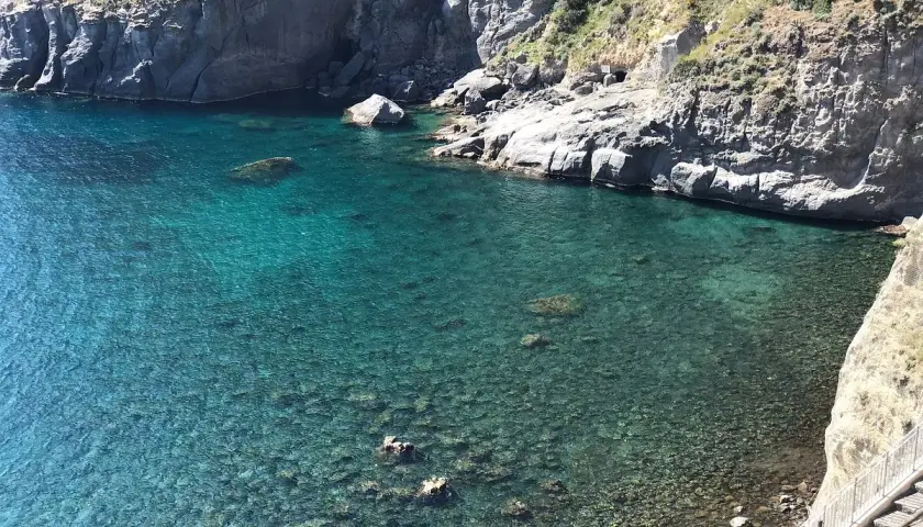 Acque cristalline e scogliere a picco a Ischia. Un angolo di paradiso dove la spiaggia incontra l'acqua calda, invitando al relax.