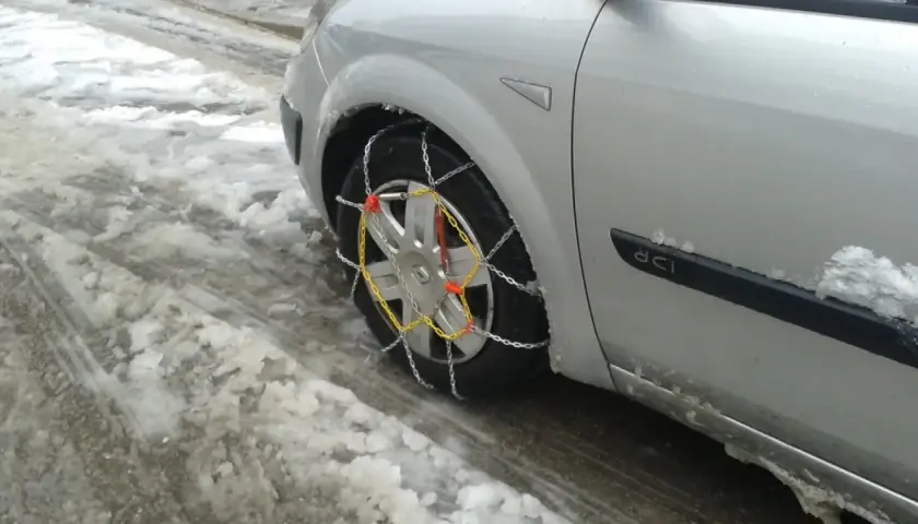 El coche está en la nieve, listo para circular cuando se ponen las cadenas de nieve.