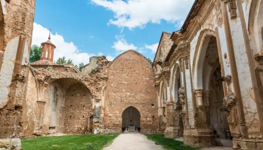 Ruinas de un antiguo convento, lugar donde se rodó Traitors España. El cielo azul con nubes contrasta con la piedra erosionada.