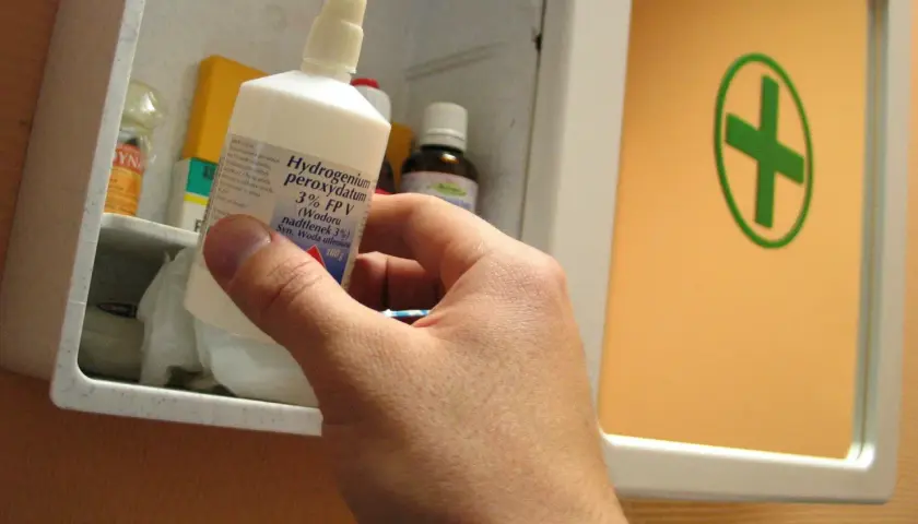 Ręka wyjmuje z apteczki butelkę z napisem "Hydrogenium peroxydatum 3% (Wodoru nadtlenek 3%) Syn. Woda utleniona". Idealna do walki z pleśnią.