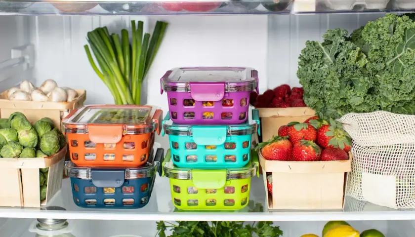 Bunte Vorratsbehälter mit Gemüse und Beeren. Oben liegen unreifes Obst und grünes Gemüse.