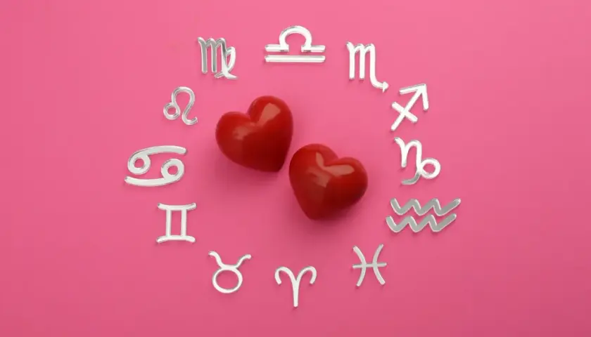 Dwa czerwone serca otoczone srebrnymi symbolami zodiaku. Dziś horoskop na dziś Waga miłosny zapowiada gorące uczucia.