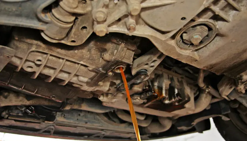 Płynny strumień oleju wypływa z automatycznej skrzyni biegów podczas jej wymiany.