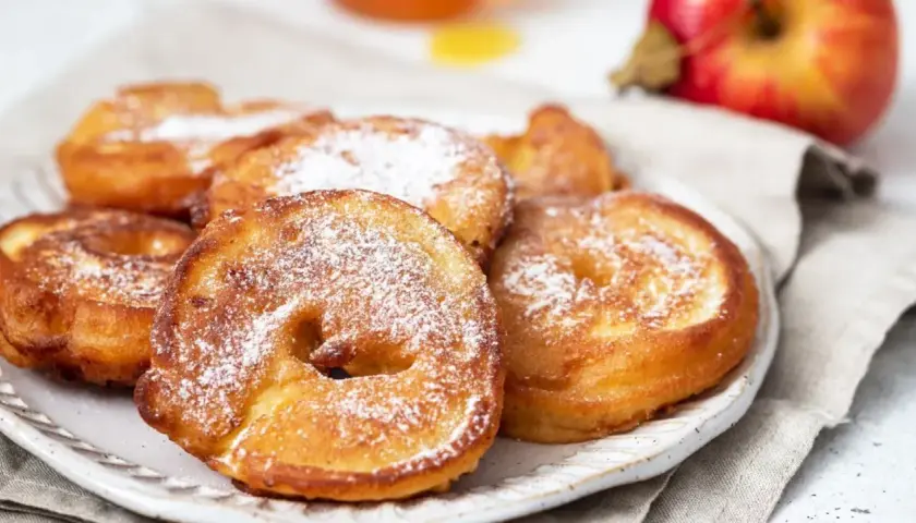 Délicieux beignets aux pommes saupoudrés de sucre glace, prêts à être dégustés.