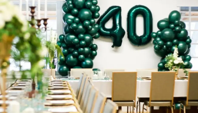 Elegancka impreza urodzinowa dla dorosłych z balonami tworzącymi liczbę 40. Uroczysty stół z zastawą i świecami.
