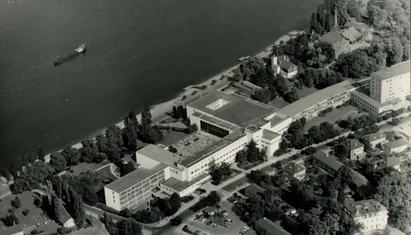 Luftaufnahme von Bonn am Rhein, als die Stadt Hauptstadt war. Mehrere Schiffe auf dem Wasser, Regierungsgebäude und Bäume.