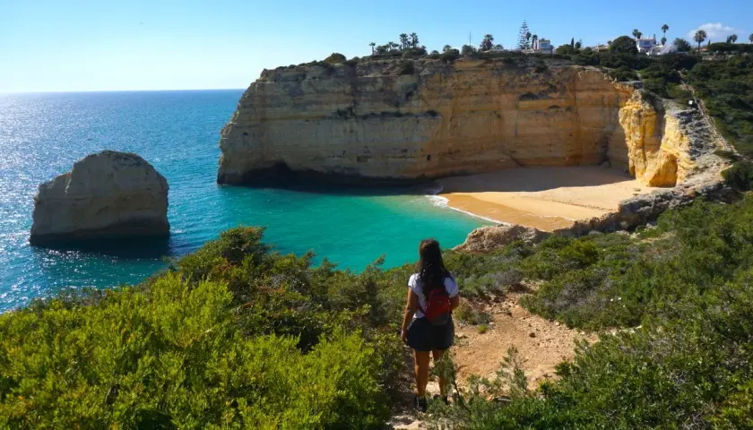 Una mujer admira las impresionantes calas del Algarve, con sus acantilados dorados y aguas turquesas.