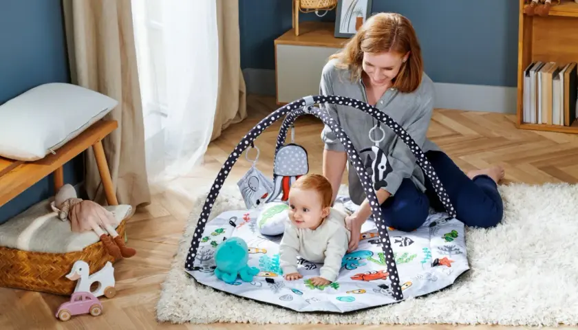 Mama bawi się z niemowlakiem na macie edukacyjnej dla niemowląt od kiedy tylko zacznie raczkować. Kolorowa mata z zabawkami zachęca do odkrywania świata.