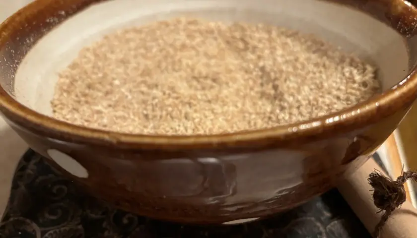 A bowl of gomo shio, a Japanese seasoning, sits on a patterned cloth.