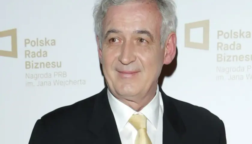 Waldemar Dąbrowski w garniturze i żółtym krawacie, z siwymi włosami, uśmiecha się. Tło z logo "Polska Rada Biznesu".