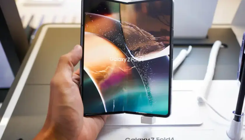 Dłoń trzyma rozłożony smartfon Galaxy Z Fold4, jeden z największych smartfonów na rynku, z kolorową tapetą.