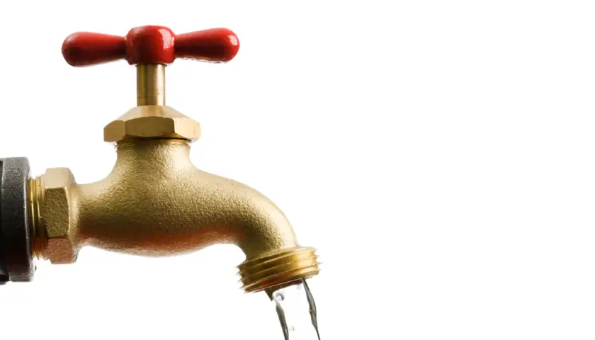 Messing-Wasserhahn mit rotem Griff, aus dem Wasser fließt. Bei Aquastop muss man den Wasserhahn zudrehen.