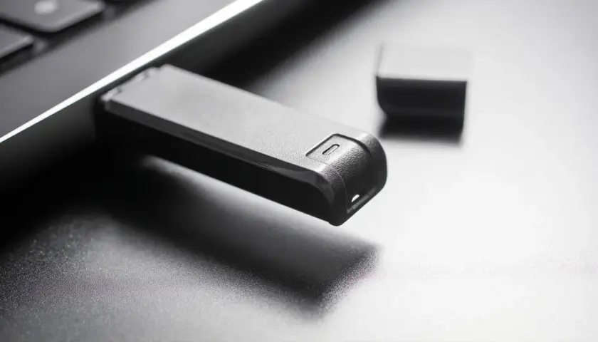 Schwarzer USB-Stick steckt in einem Laptop. Die Frage "usb stick formatieren welches format" wird durch das Bild angeregt.