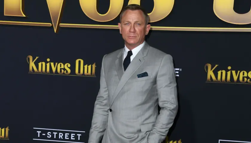 Daniel Craig trägt einen eleganten hellgrauen Anzug mit einem dunkelblauen Einstecktuch.
