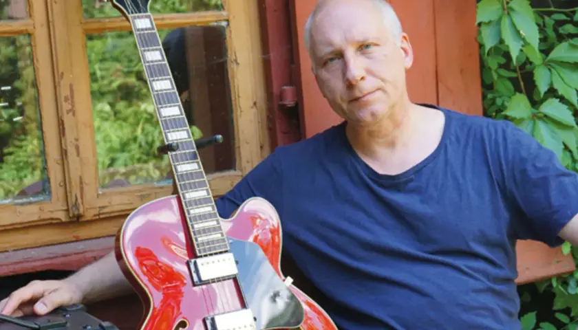 Kuba Sienkiewicz z zespołem przygotowuje się do koncertu. Czerwona gitara i wzrok pełen skupienia.