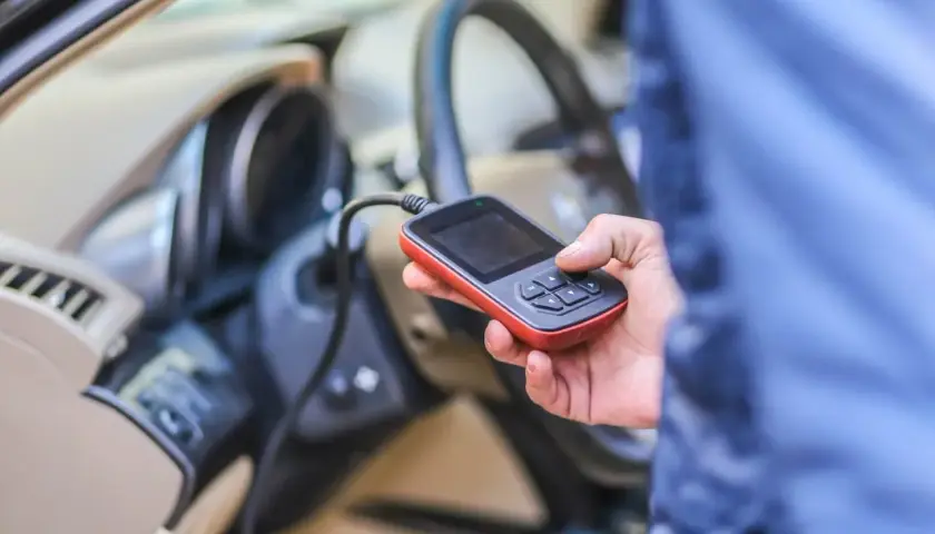 Diagnostyka Renault: ręka trzyma skaner OBD, który może pomóc rozwiązać problem DTC B1267.
