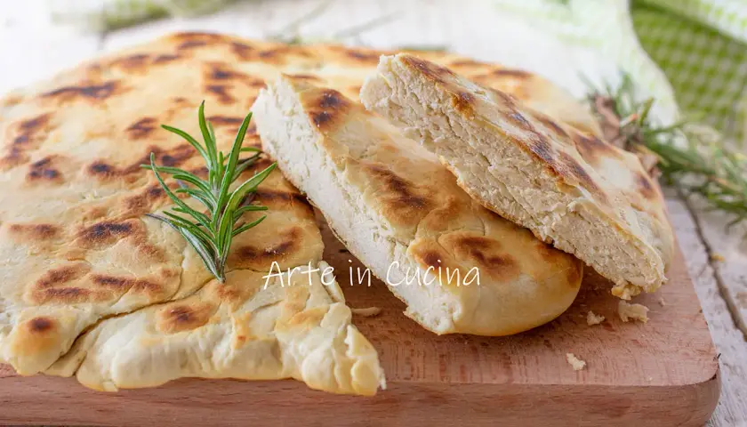 Una crescia umbra appena sfornata, dorata e profumata, con un rametto di rosmarino fresco.