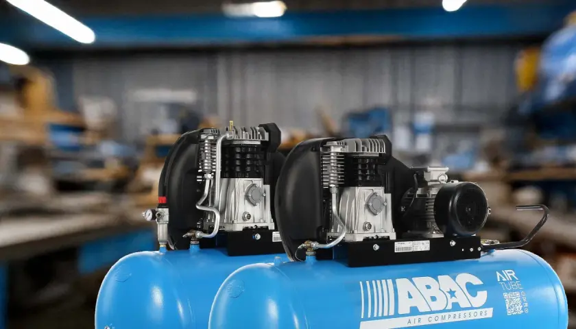 Dos compresores de aire ABAC con motor eléctrico y cabezal de pistón, un tipo de compresor reciprocante, listos para trabajar.