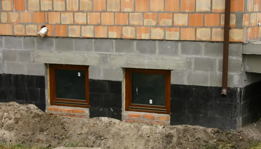 Fundamenty starego domu z oknami i izolacją przeciwwilgociową. Czy ocieplać fundamenty w starym domu? Rozważamy termoizolację.