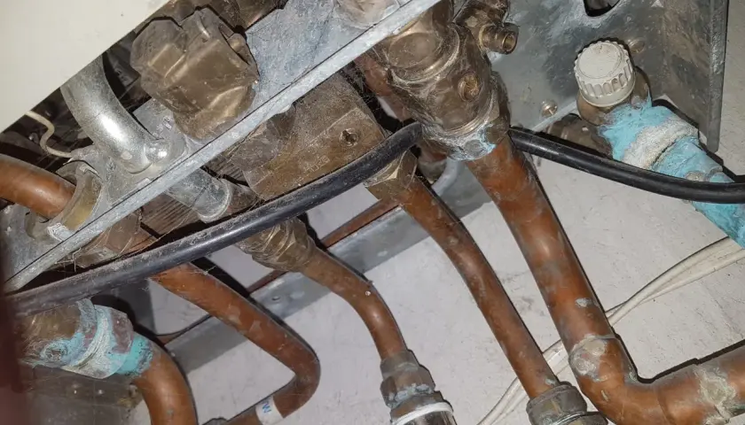 Instalacja pieca gazowego Vaillant z miedzianymi rurami. Widoczne przyłącza i zawory, być może problem ze słabym ciśnieniem ciepłej wody.