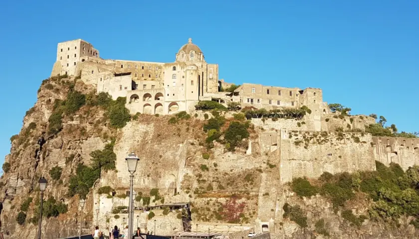 Il Castello Aragonese di Ischia, con i suoi orari e prezzi da scoprire, domina la roccia. Un ponte conduce all'imponente fortezza.
