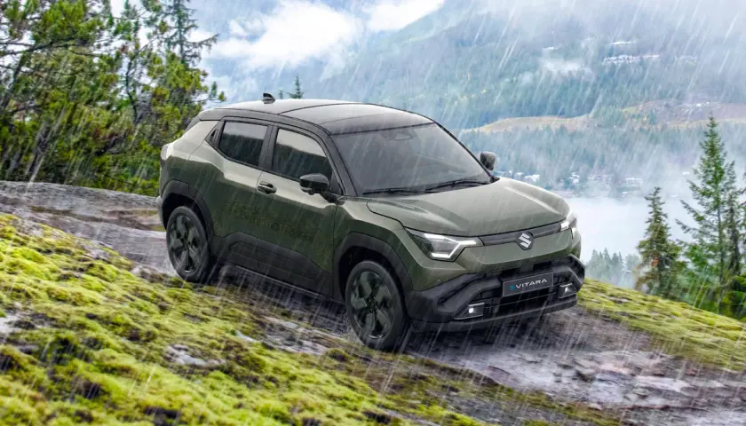 Grön Suzuki Vitara med automatisk växellåda kör på en mossig, stenig sluttning i regn.