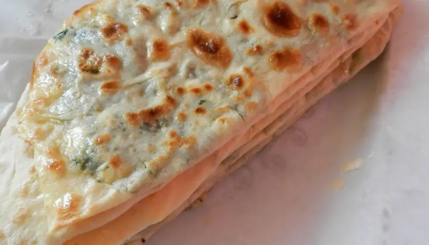Gozleme épinard, une crêpe turque dorée et pliée, garnie d'épinards frais et savoureux.