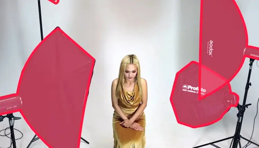 Modelka w złotej sukni, otoczona różnymi rodzajami oświetlenia w fotografii studyjnej.