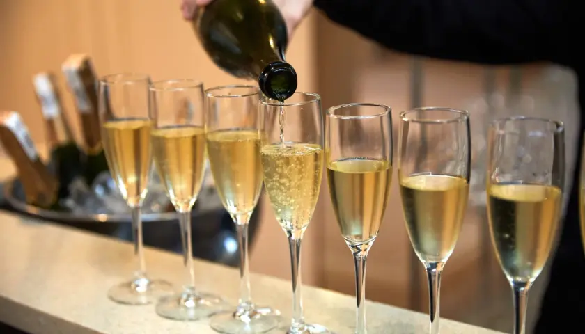Eine Flasche italienischer Champagner wird in eine Reihe von Gläsern eingeschenkt.
