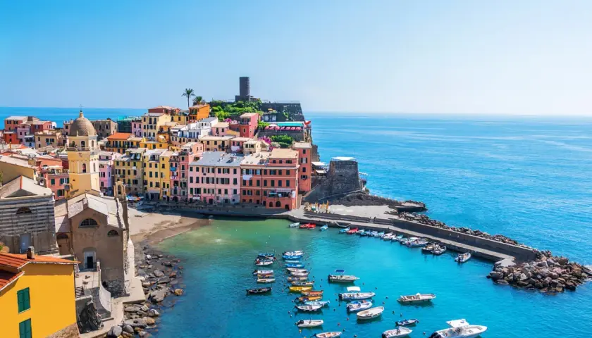 Vue pittoresque des 5 Terres en camping-car : maisons colorées, église, port animé et mer azur.