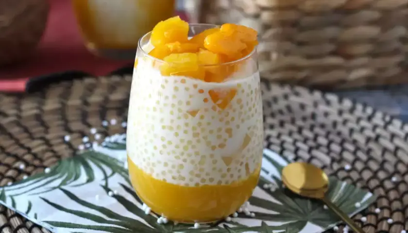 En glas med krämig mango sago, toppad med färsk mango. En tropisk dröm!