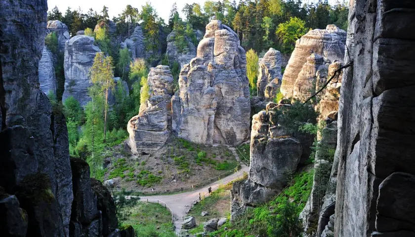 Skalne miasto w Czechach, labirynt piaskowcowych wież i wąskich przejść, otoczony zielenią.