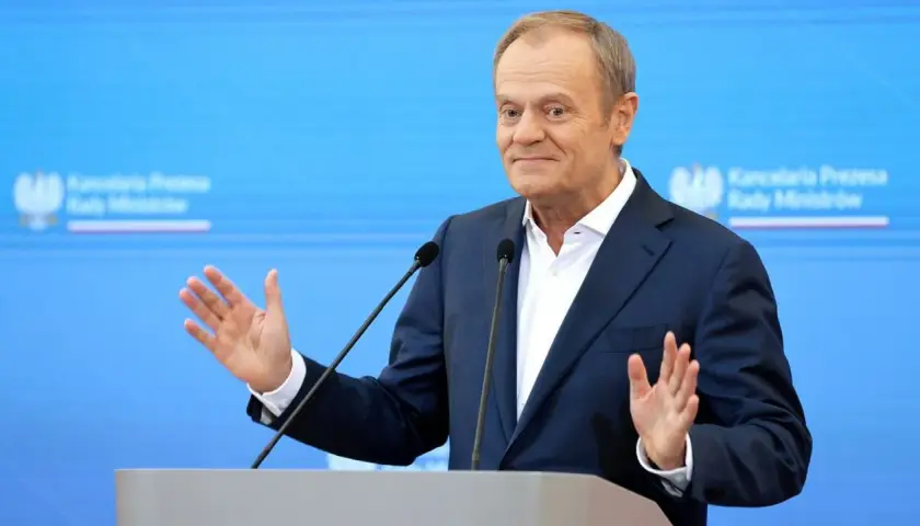 Donald Tusk przemawia, gestykulując. W tle logo Kancelarii Premiera. Czy zastanawiasz się, ile zarabia Tusk miesięcznie?