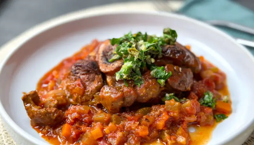 Herzhaftes Ossobuco mit einer reichhaltigen Tomaten-Gemüse-Sauce und frischer Kräuter-Gremolata als Beilage.