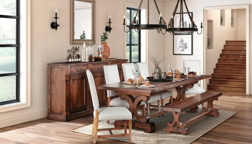 A rustic dining room featuring a dark wood table with ornate legs, upholstered chairs, and a matching bench. This sturdy, beautiful wood is the best wood for kitchen table.