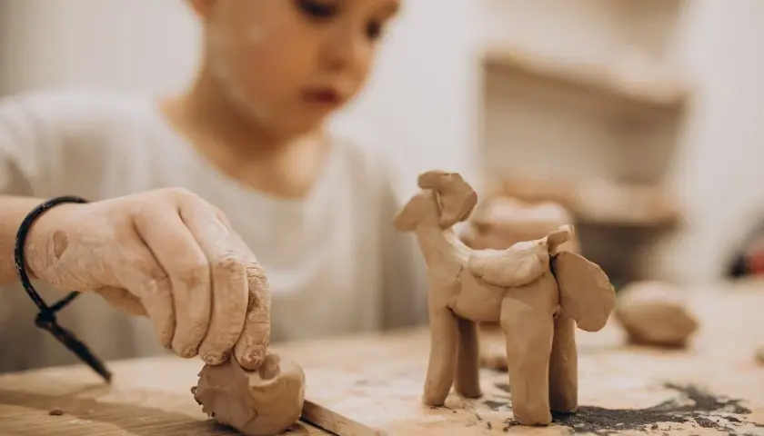 Niño de 2-3 años creando un caballito con arcilla. Divertidas actividades con arcilla para pequeños artistas.