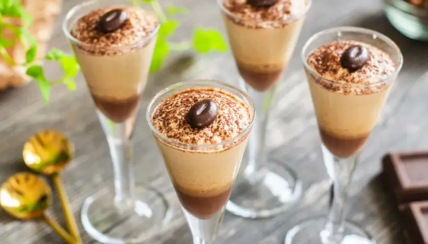Quattro bicchieri di deliziosa mousse al caffè, spolverata di cacao e guarnita con un chicco di caffè.