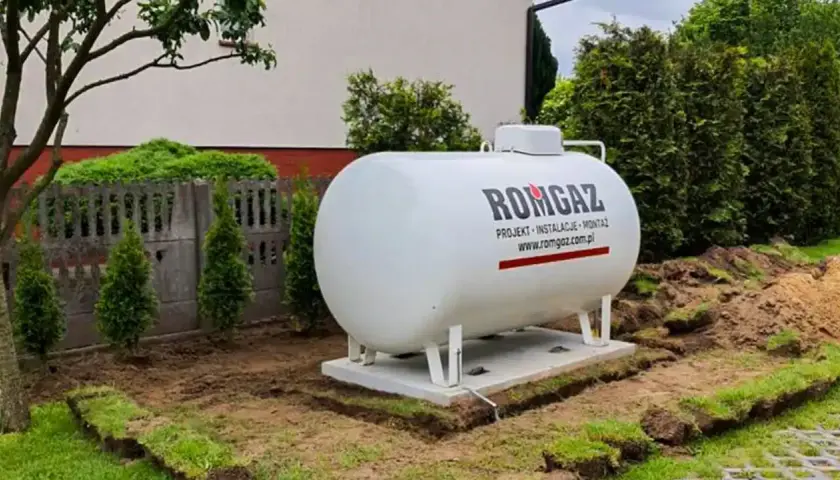 Zbiornik gazu ROMGAZ, kluczowy do określenia, ile metrów sześciennych gazu na ogrzanie domu, stoi na fundamencie w ogrodzie.