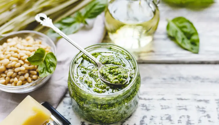 Pesto bazyliowe w słoiku, obok orzeszki piniowe, ser parmezan i oliwa. Idealne do makaronu, na grzanki i do sałatek.