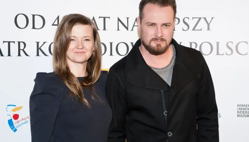 Paweł Małaszyński z żoną, uśmiechnięci na tle napisu "Teatr Komedia".